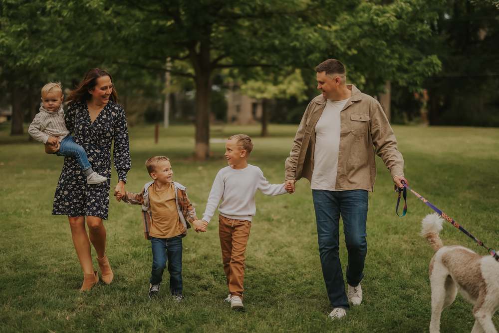 A family walking the park with their dog