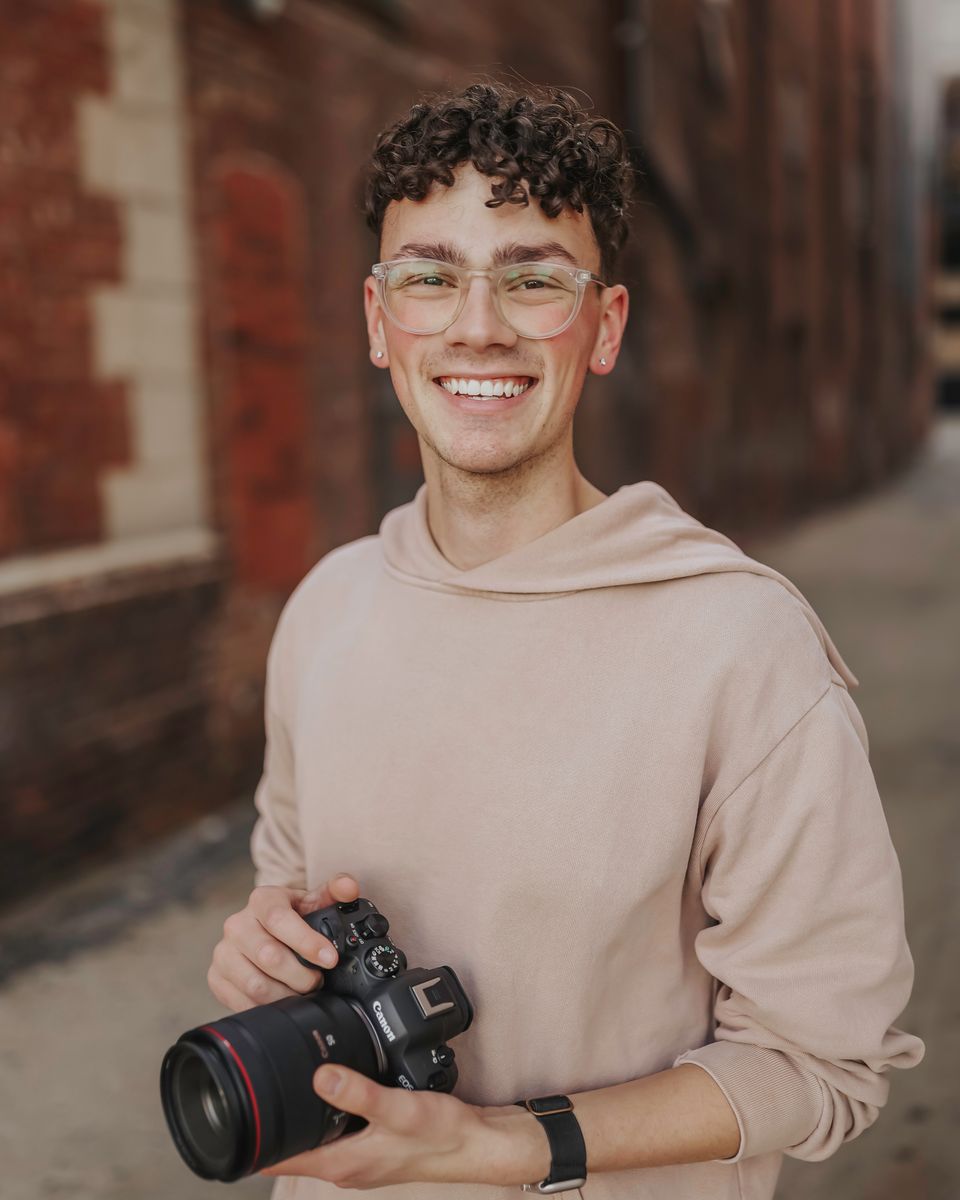 Evan Allen holding his camera in a brick alley