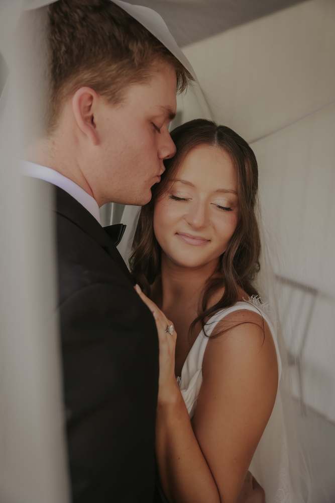 A kiss on the temple against the white wall